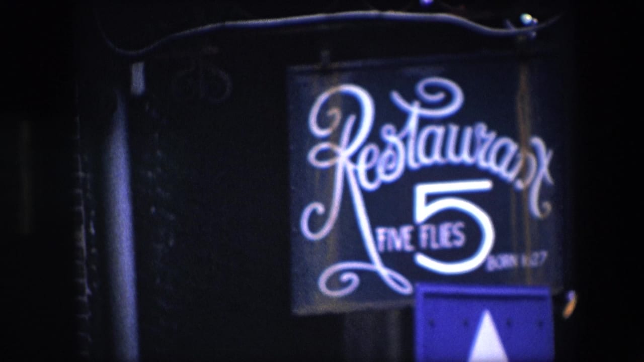Restaurant Five Flies sign glowing against a dark exterior wall.