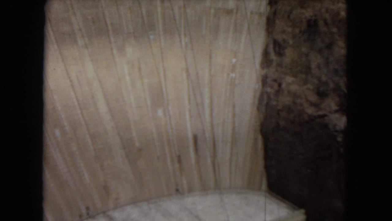 1967 Arizona frame showing Glen Canyon Dam's pale concrete curve above part of the power plant and dark canyon rock.