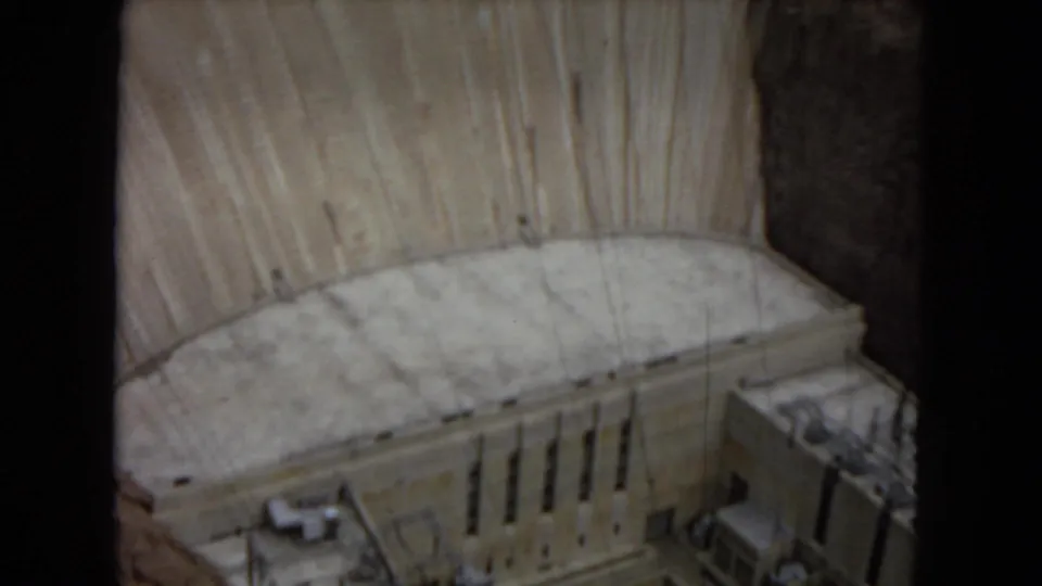 Visitor-shot 1967 frame of Glen Canyon Dam, showing the lower concrete face, power plant building, and adjacent canyon wall.