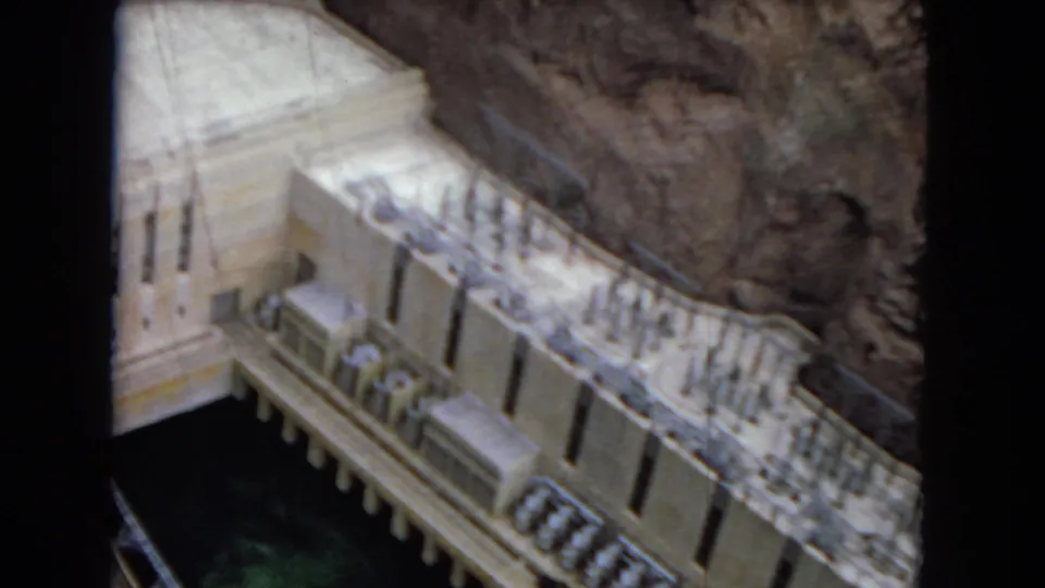1967 8mm view of the Boulder Dam or Hoover Dam concrete face and structural details between steep canyon walls, with dark film borders visible.