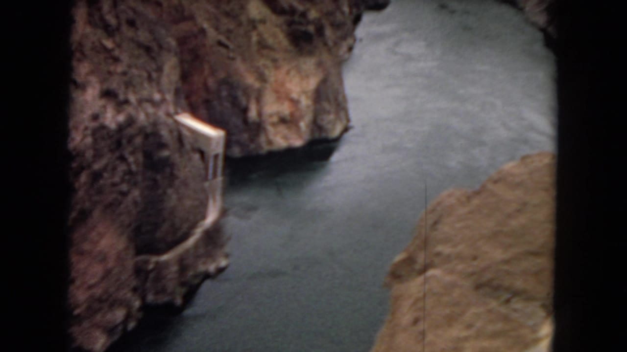 Canyon river curving past steep rock with a concrete intake or spillway structure on the left bank.