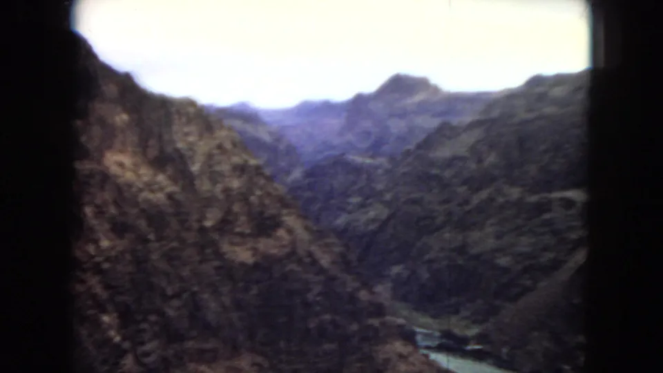 A wide view from the same travel film shows a deep rocky gorge and distant mountains, with the river visible far below through the canyon.