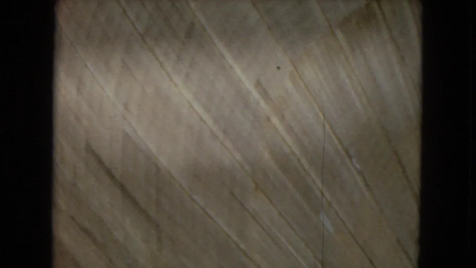Soft 8mm frame dominated by pale diagonal streaks and film grain, with no identifiable people, signs, or structures.