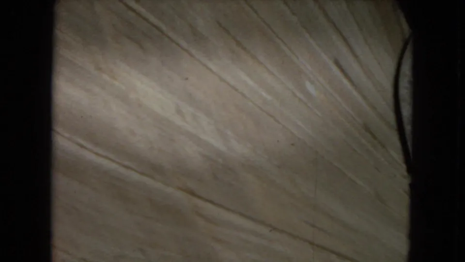 1967 8mm frame showing a close, downward view of pale concrete or dam surface with dark vertical structural edges at the sides.