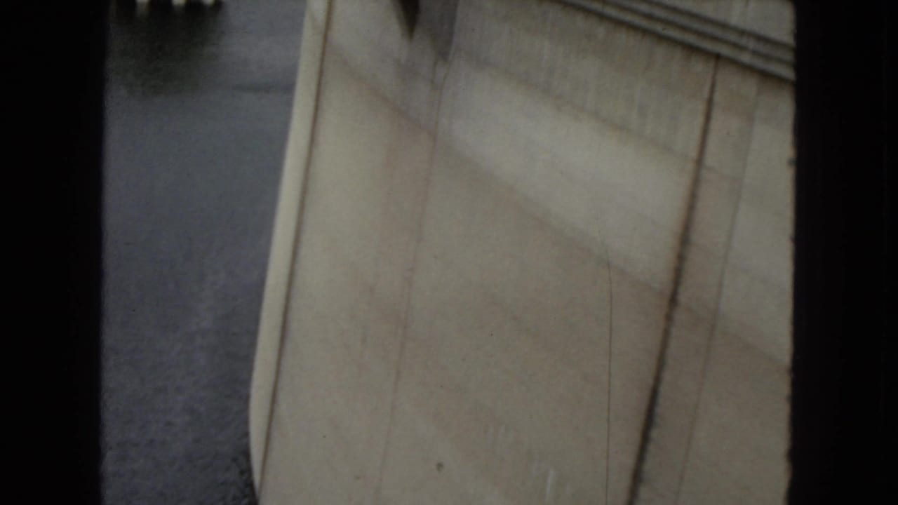 Close 1967 home-movie view of Hoover Dam concrete and adjacent water, framed tightly with soft focus and black 8mm borders.