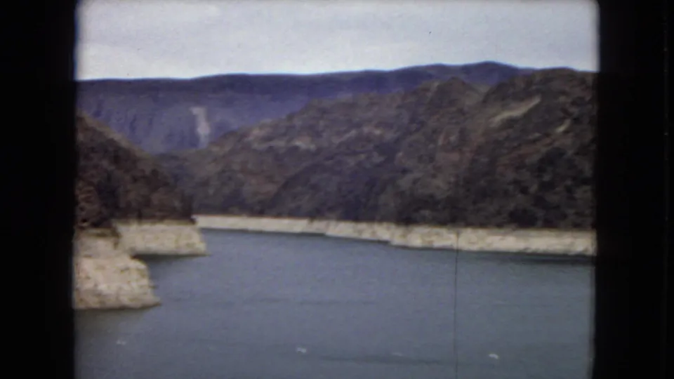 The reservoir near Hoover Dam stretches between rugged desert mountains, seen in a soft 1967 home-movie landscape frame.