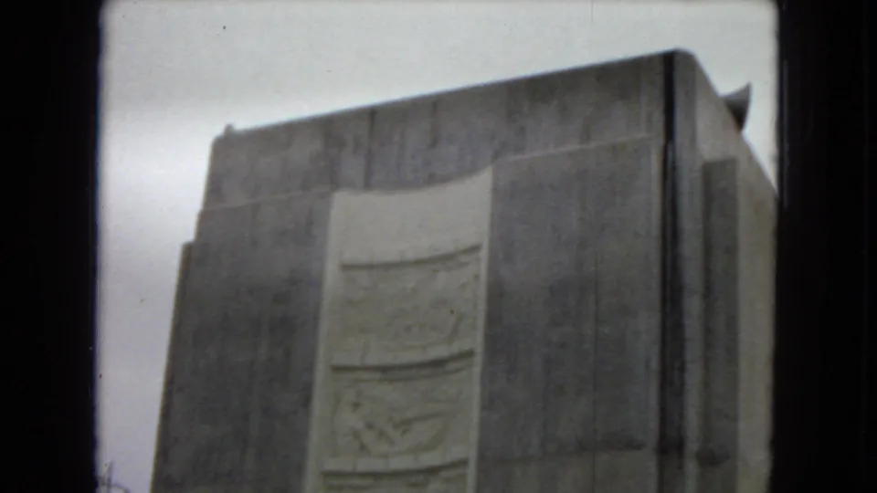 1967 Arizona home-movie frame showing a large concrete dam wall or tower with a recessed decorative panel, filmed from a low visitor viewpoint.