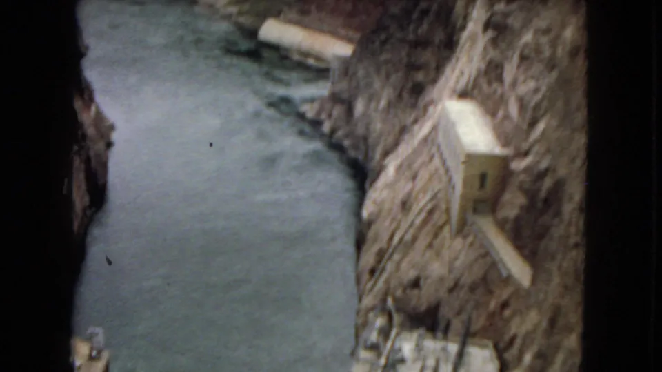 1967 Arizona 8mm frame showing a narrow blue-green river channel between rock walls, with concrete infrastructure set into the canyon side.