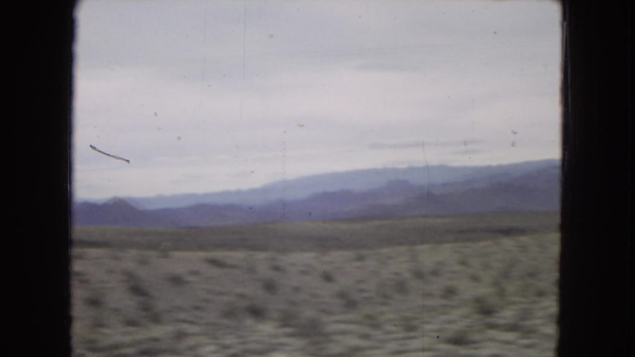 Open desert and mountain ridges framed by a vehicle window.