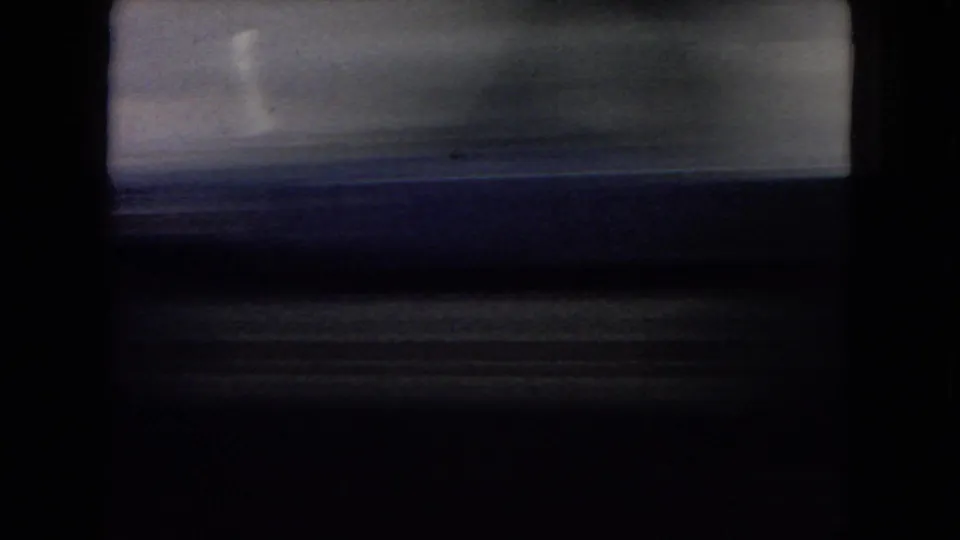 Motion-blurred 8mm view from a moving car in the Arizona desert, showing dark sky, low land, and the edge of the vehicle interior or window frame.