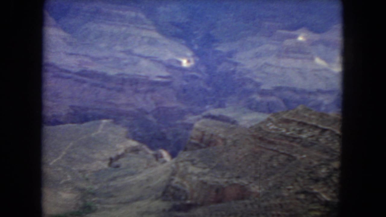 1967 Grand Canyon travel footage frame with a broad high-vantage view across terraced rock formations and shadowed canyon depth.
