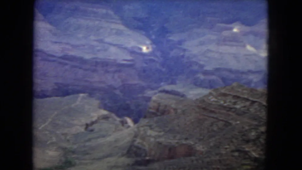 1967 Grand Canyon travel footage frame with a broad high-vantage view across terraced rock formations and shadowed canyon depth.