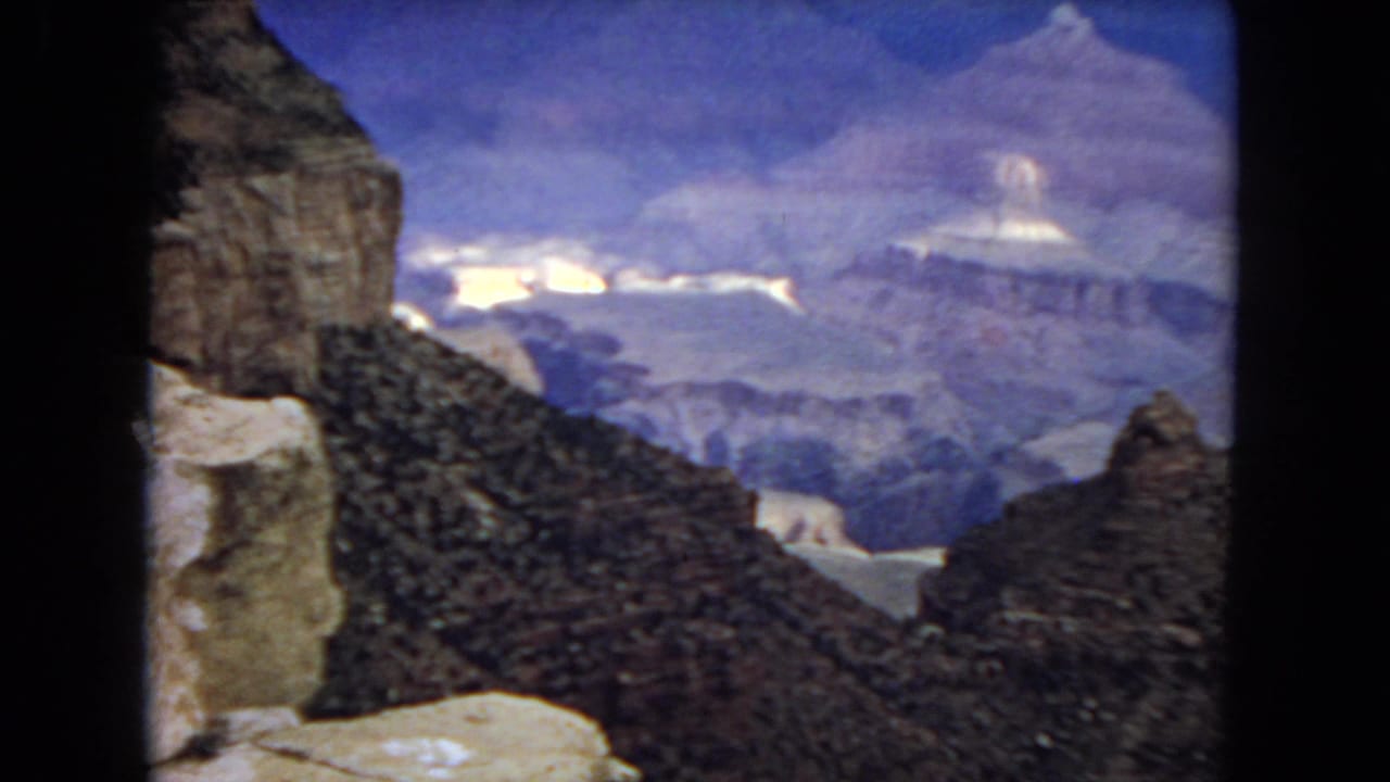 Canyon walls and mesas seen between dark rock formations.