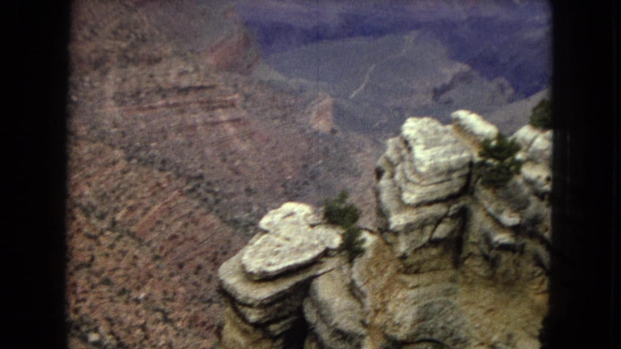 1967 Arizona home-movie frame showing pale cap-like rock formations above layered Grand Canyon ravine walls.