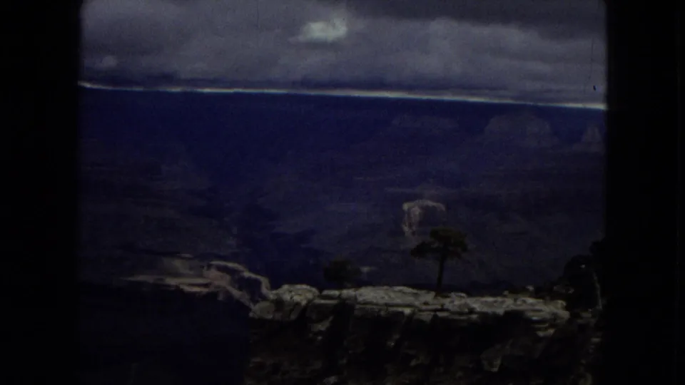 Moody 1967 Arizona home-movie frame showing a distant Grand Canyon vista with a lone tree and overcast sky.