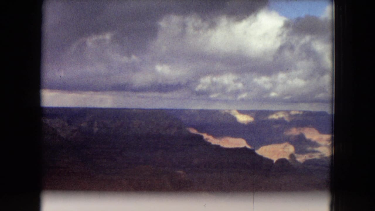 1967 Arizona canyon panorama showing layered Grand Canyon formations, winding ravines, and broken cloud cover across the distant horizon.