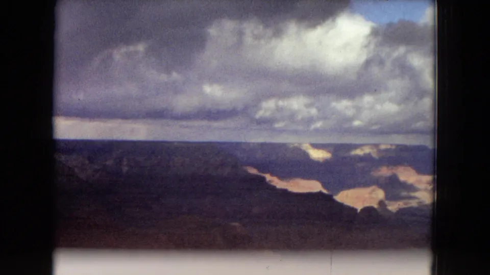 1967 Arizona canyon panorama showing layered Grand Canyon formations, winding ravines, and broken cloud cover across the distant horizon.