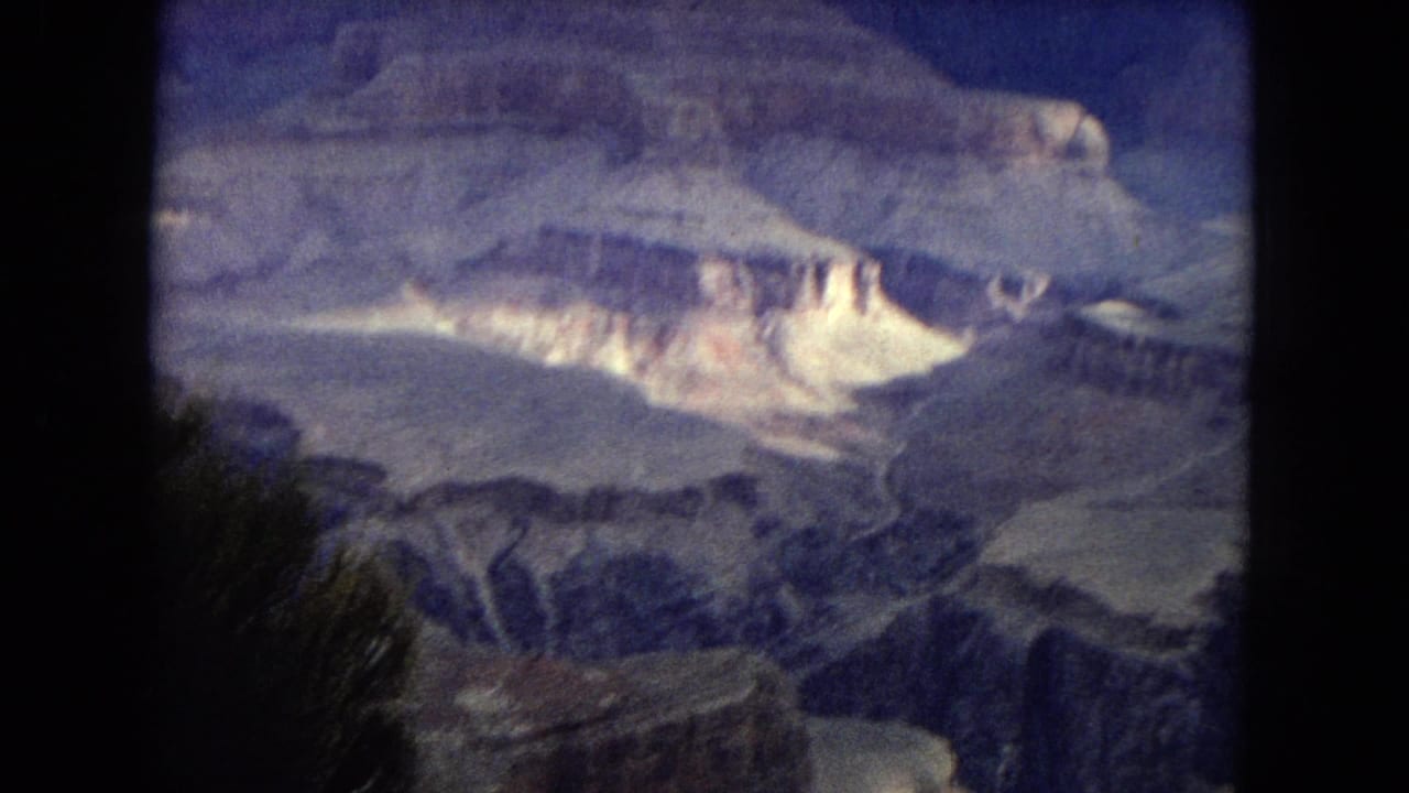 1967 Arizona 8mm frame showing Grand Canyon rock layers, a deep valley, and dark contact-sheet borders around the scanned home-movie image.