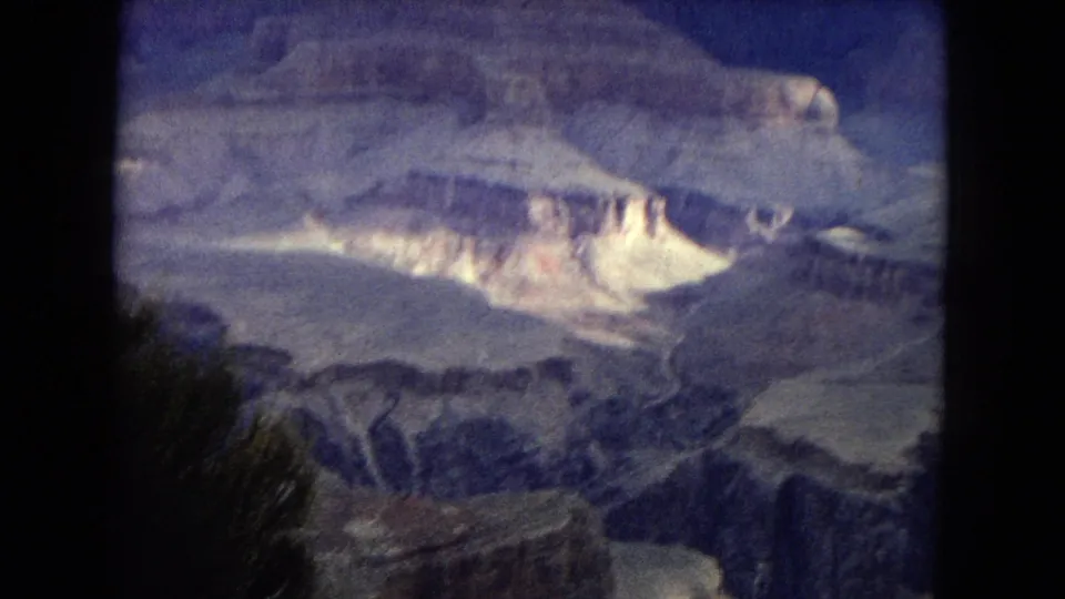1967 Arizona 8mm frame showing Grand Canyon rock layers, a deep valley, and dark contact-sheet borders around the scanned home-movie image.