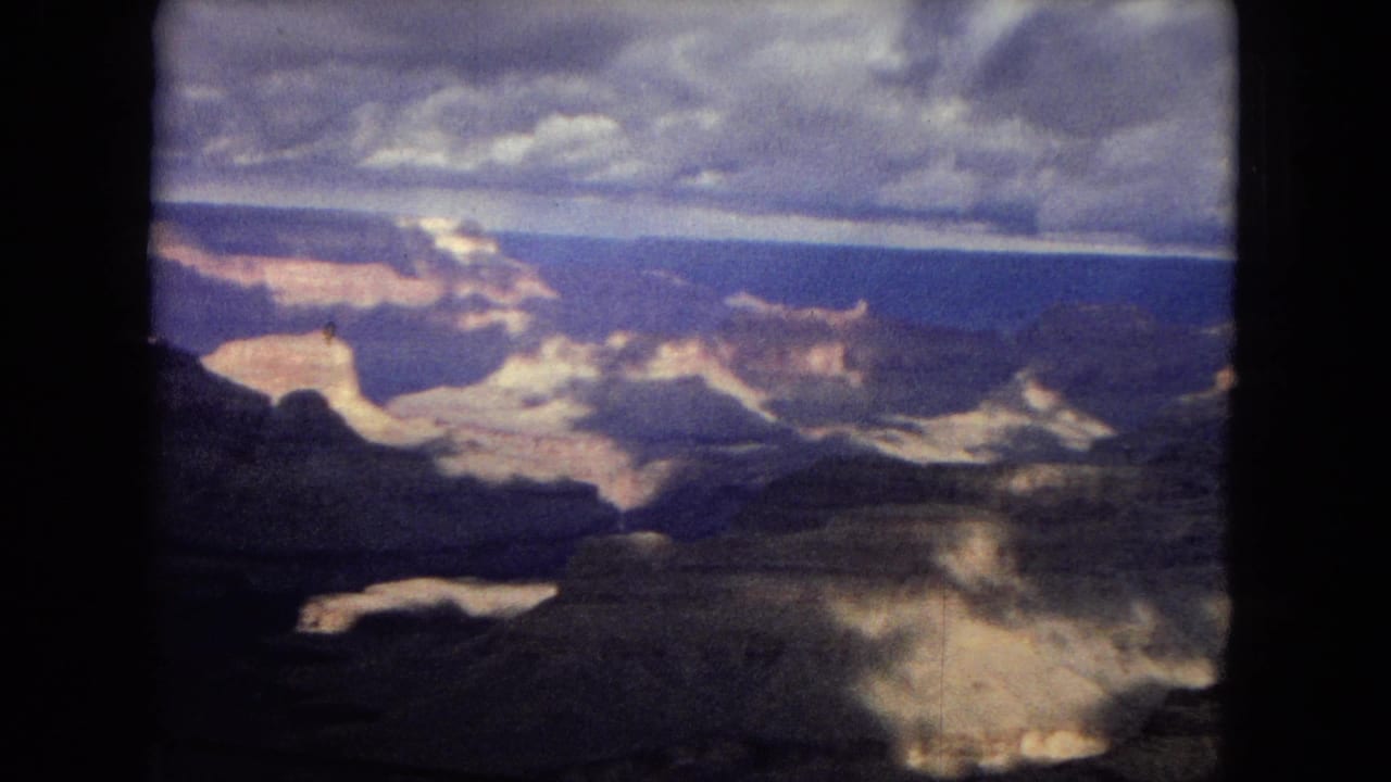 Canyon panorama with bright rock formations and dark clouds in a film-frame border.