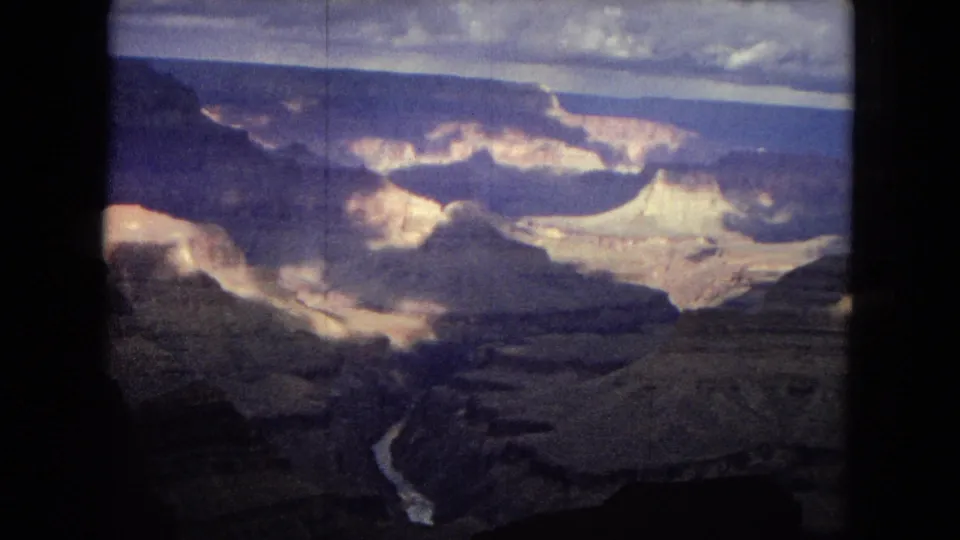 Aerial 8mm view of the Grand Canyon with the Colorado River appearing as a narrow bright line through the lower canyon floor.