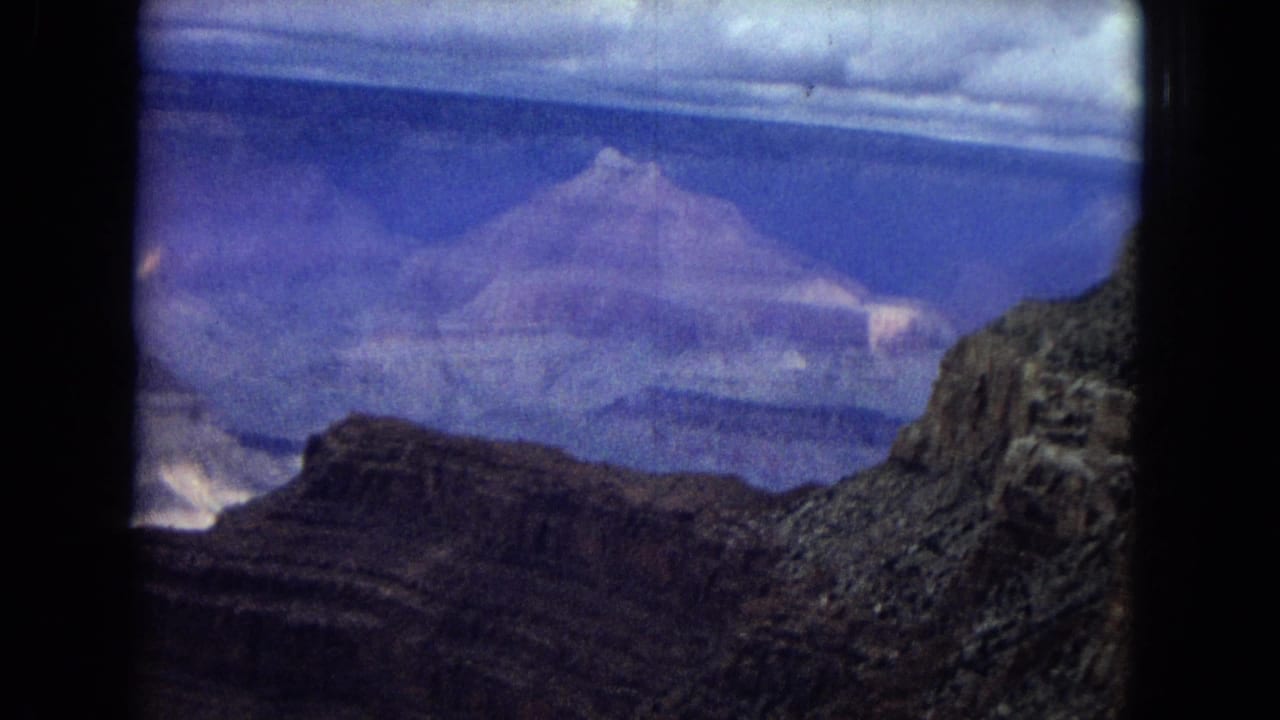 Distant canyon plateau and shadowed gorge with blue-toned sky and frame edge darkness.