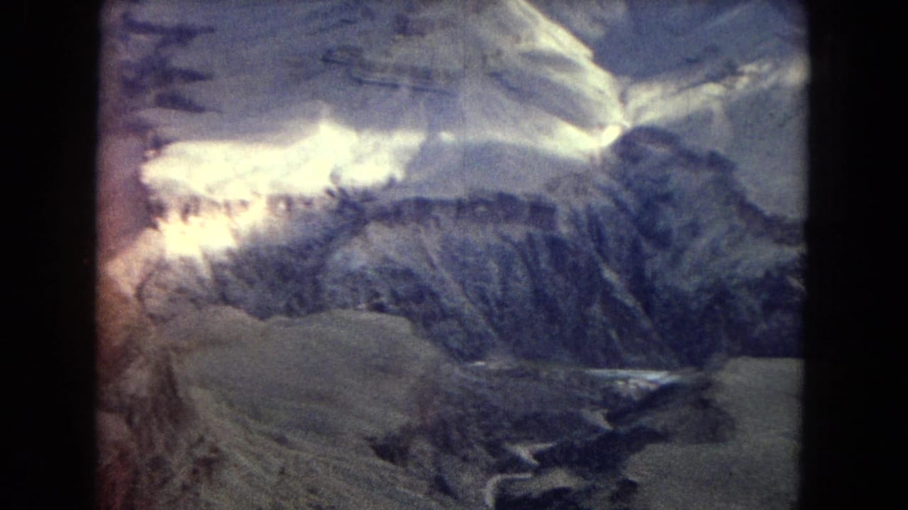 1967 8mm Arizona travel footage appears to show snow-dusted canyon and mountain ridges under clouded light, with dark frame edges and faded color.