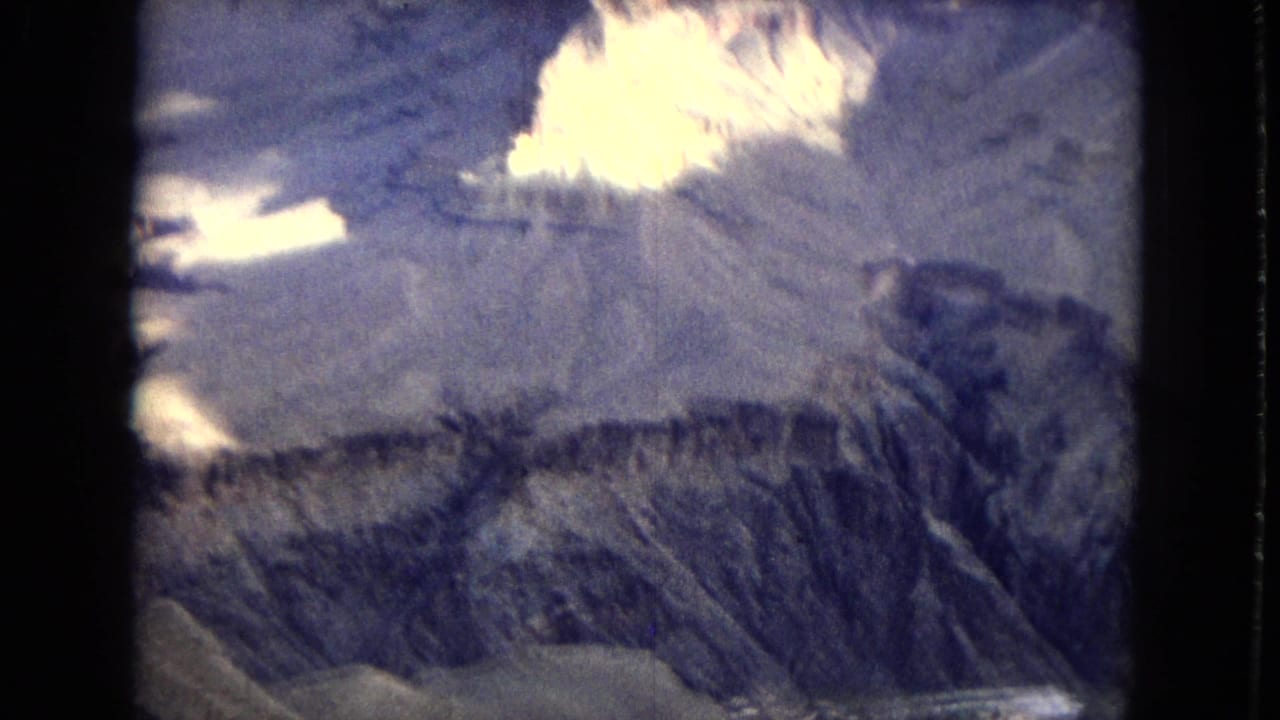 1967 Arizona home-movie frame appearing to show the Grand Canyon with layered rock walls, bright evening highlights, and blue shadowed terrain.