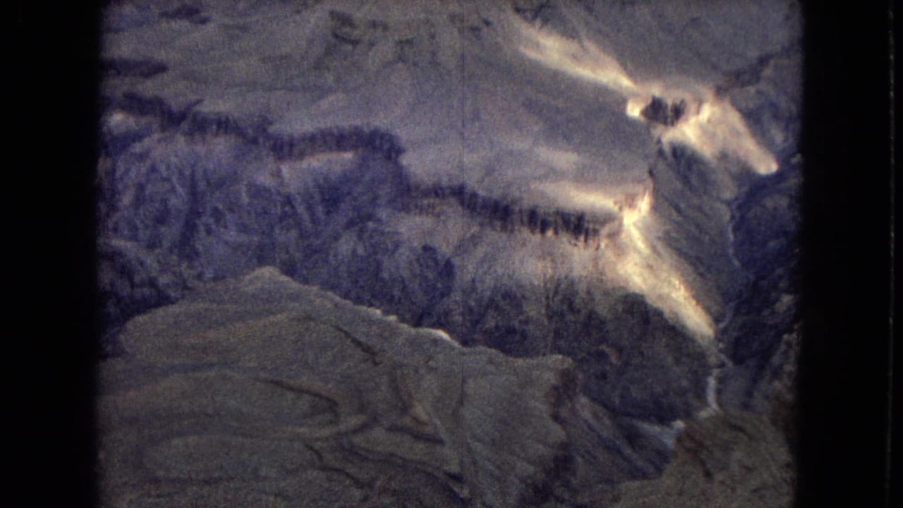 1967 8mm home-movie view of the Grand Canyon in Arizona, showing layered rock walls, deep shadow, and the Colorado River winding through the canyon floor.
