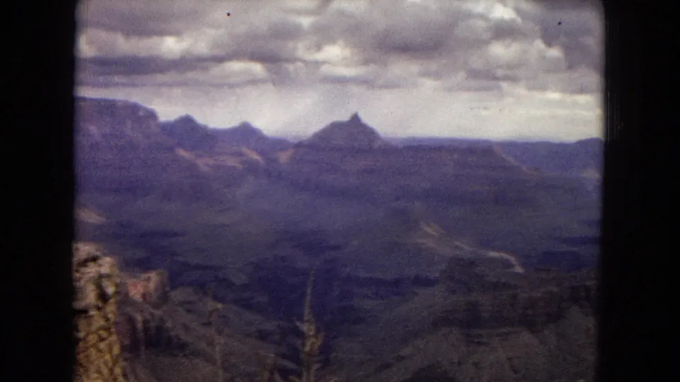 Grand Canyon vista in 1967 home-movie footage, showing broad shadowed canyon layers, distant pointed formations, and an overcast sky.