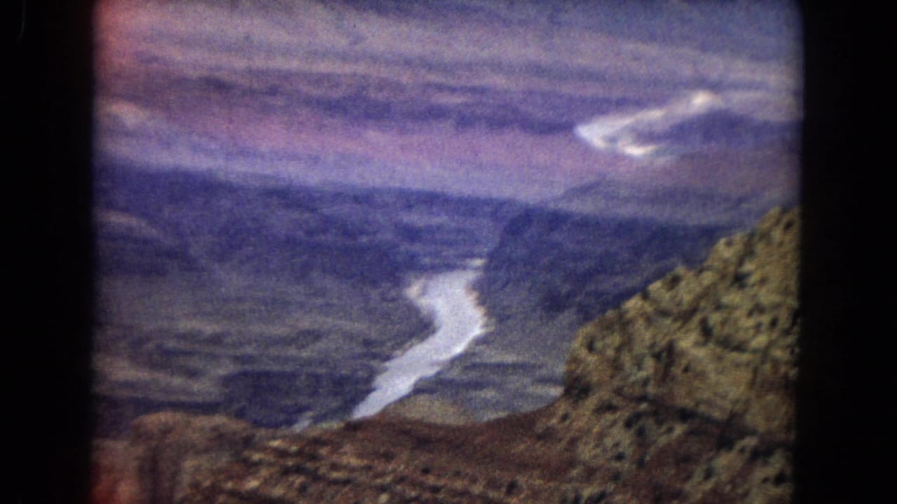 Winding river below broad canyon walls with rocky slopes at the right edge.