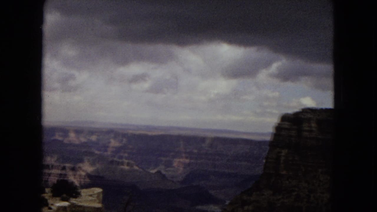Grand Canyon panorama with a large cliff face on the right under heavy clouds.