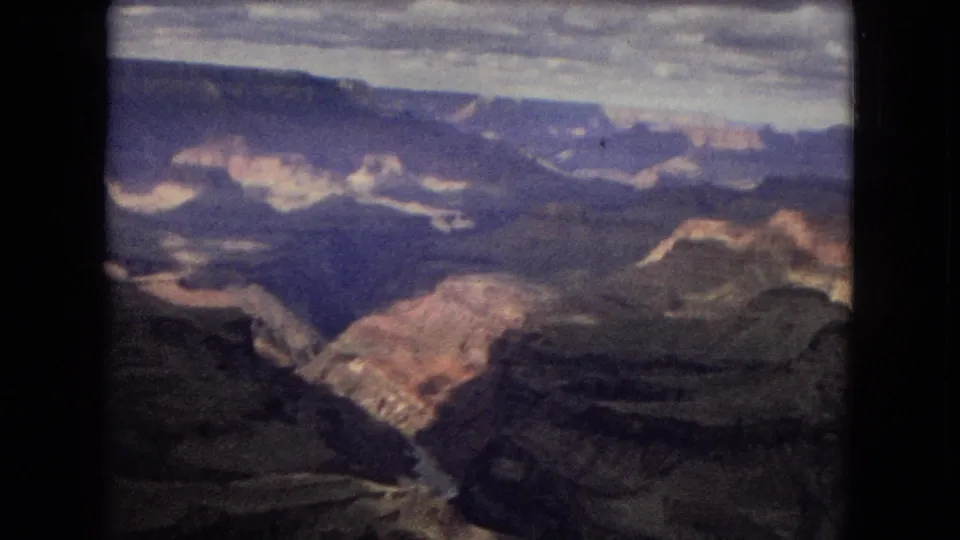 1967 8mm Grand Canyon view looking down toward layered rock walls and a winding river or wash in the canyon floor.