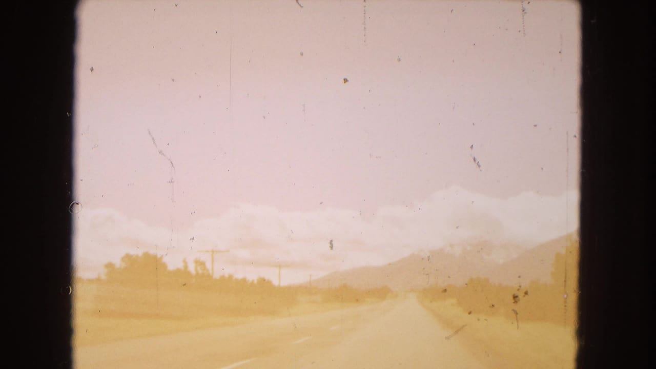 Highway and desert roadside receding toward hazy mountains.