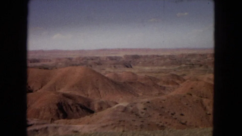 Final 1967 8mm frame of the Painted Desert area with red-brown hills, shallow gullies, and open sky across the horizon.