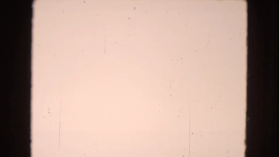 Very light 8mm frame from the Arizona driving sequence, showing mostly pale sky with faint desert ground and prominent film dust and scratches.