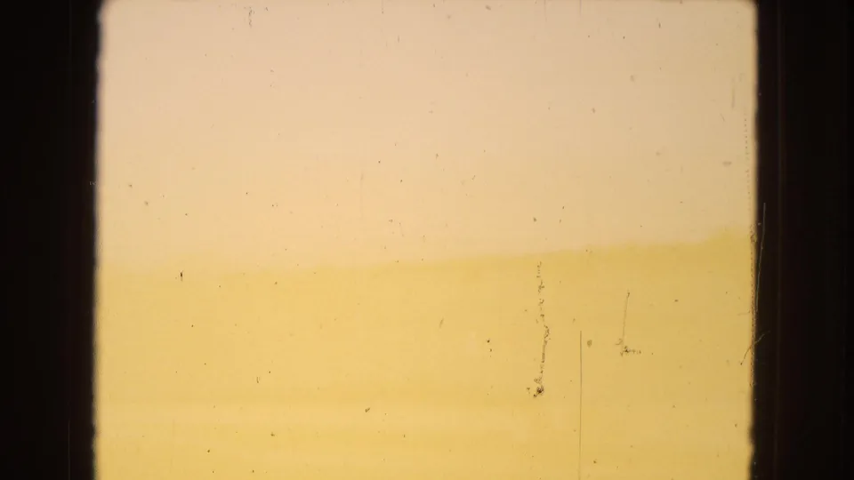 Warm, hazy 1967 Arizona desert horizon seen through a dark window-like frame, with pale sky, soft landforms, and visible 8mm dust and scratches.