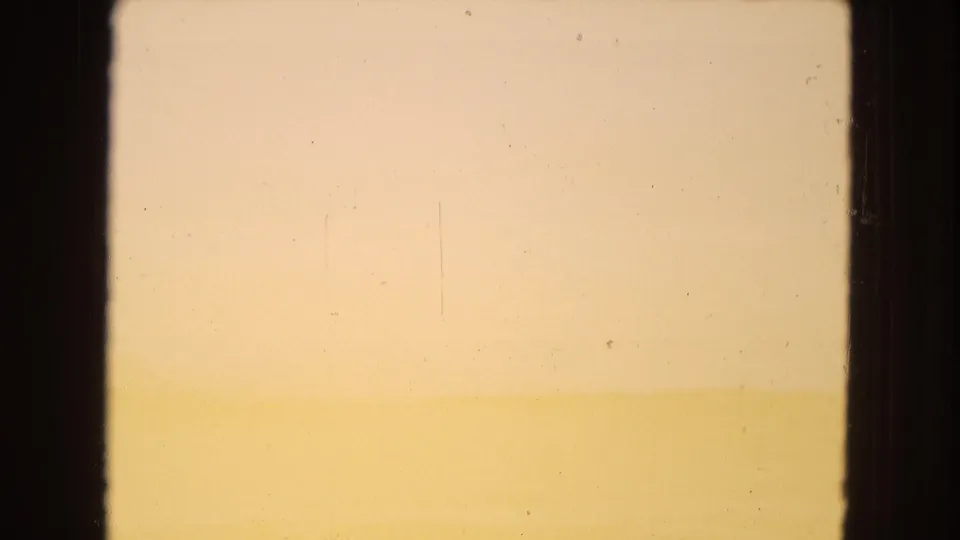 Soft orange-toned desert horizon, likely from the same 1967 Arizona road-trip footage, with dark side framing, gentle exposure wash, and visible film scratches.