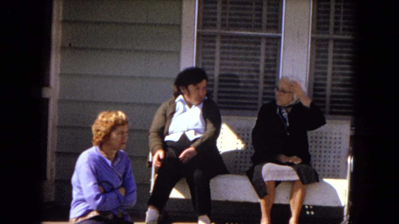 Three women remain on the porch as the elderly woman adjusts her head scarf.