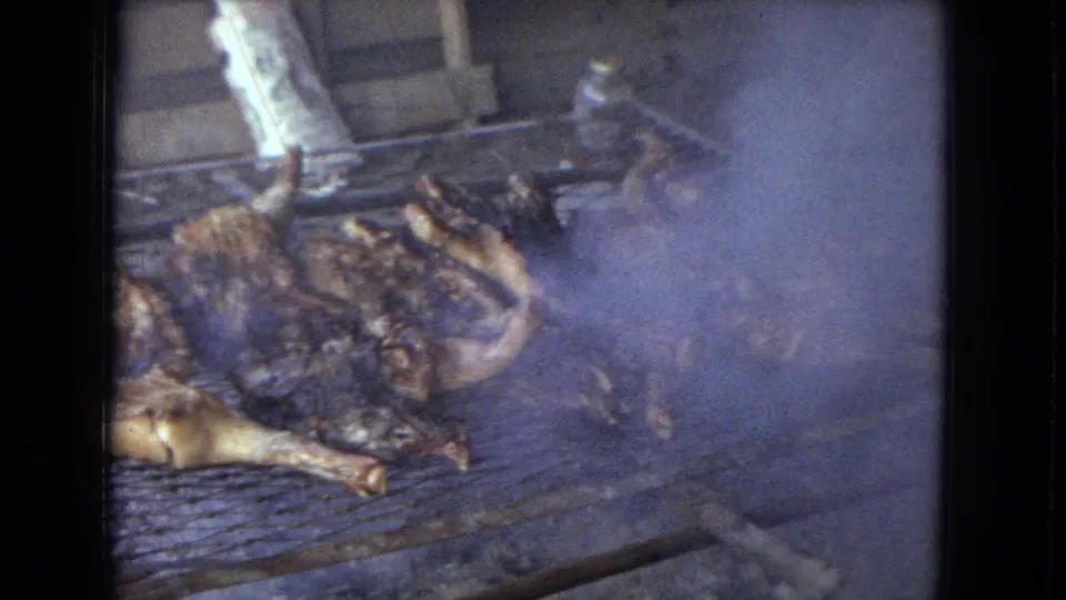 Smoke partially obscures whole chickens on a makeshift grill in this 1967 Arizona home-movie frame of rural open-fire cooking.