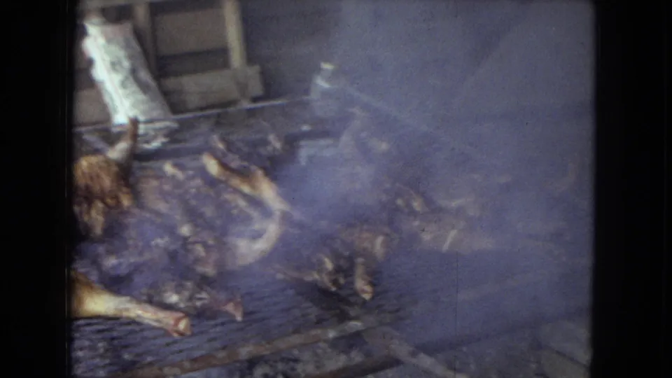 The final 1967 Arizona frame holds on smoky whole chickens roasting over a makeshift grill, with a rustic shed wall behind them.