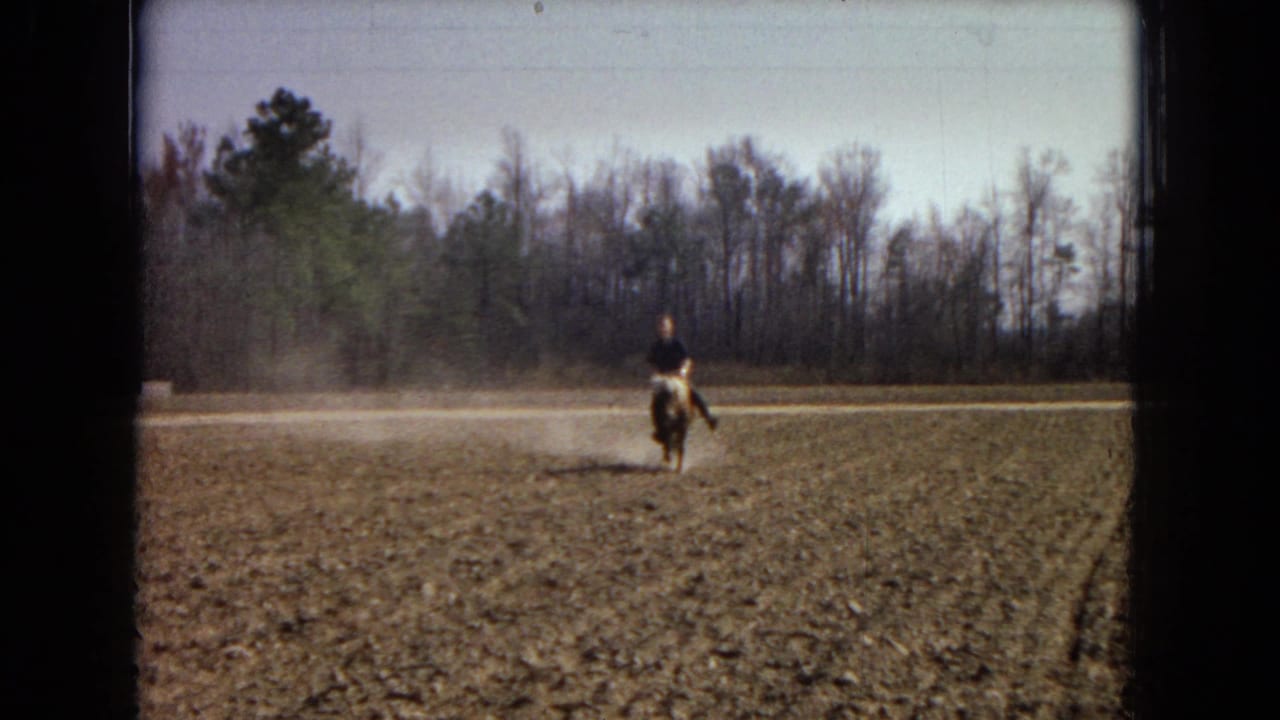 Rider on a pony approaches across a field with dust rising behind.