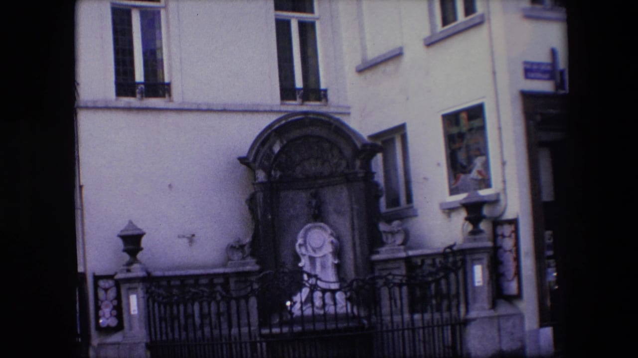 Closer view of the stone shrine, iron fence, pale wall, windows, and sign edge.