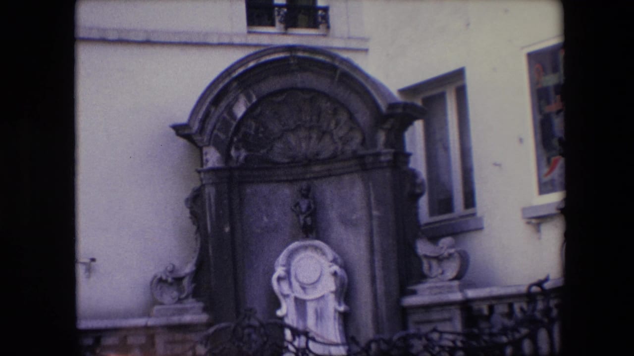 Closer view of the arched fountain, small statue, iron fence, and surrounding windows.