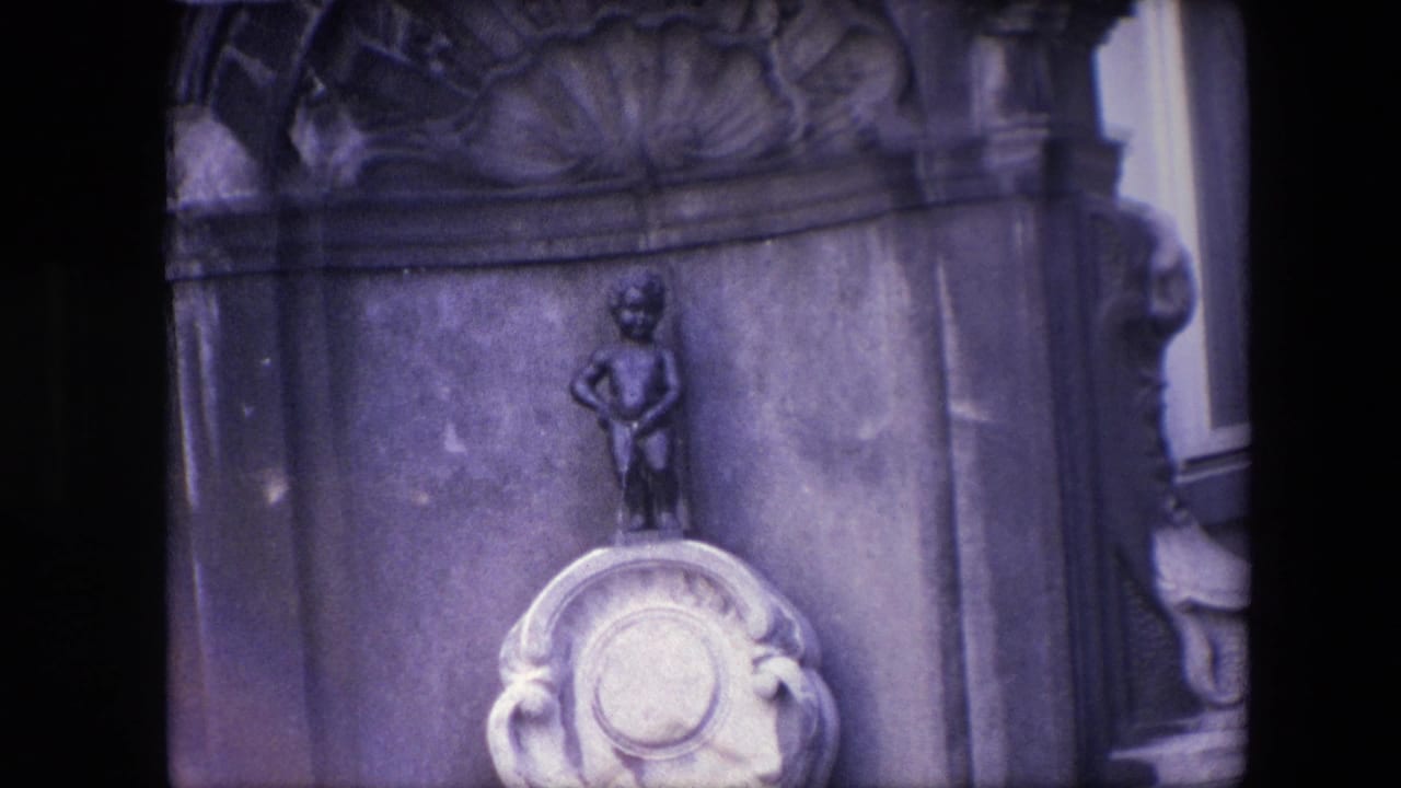 1967 Brussels 8mm frame showing the Manneken Pis figure above an ornate stone pedestal, with carved masonry and dark film borders visible.