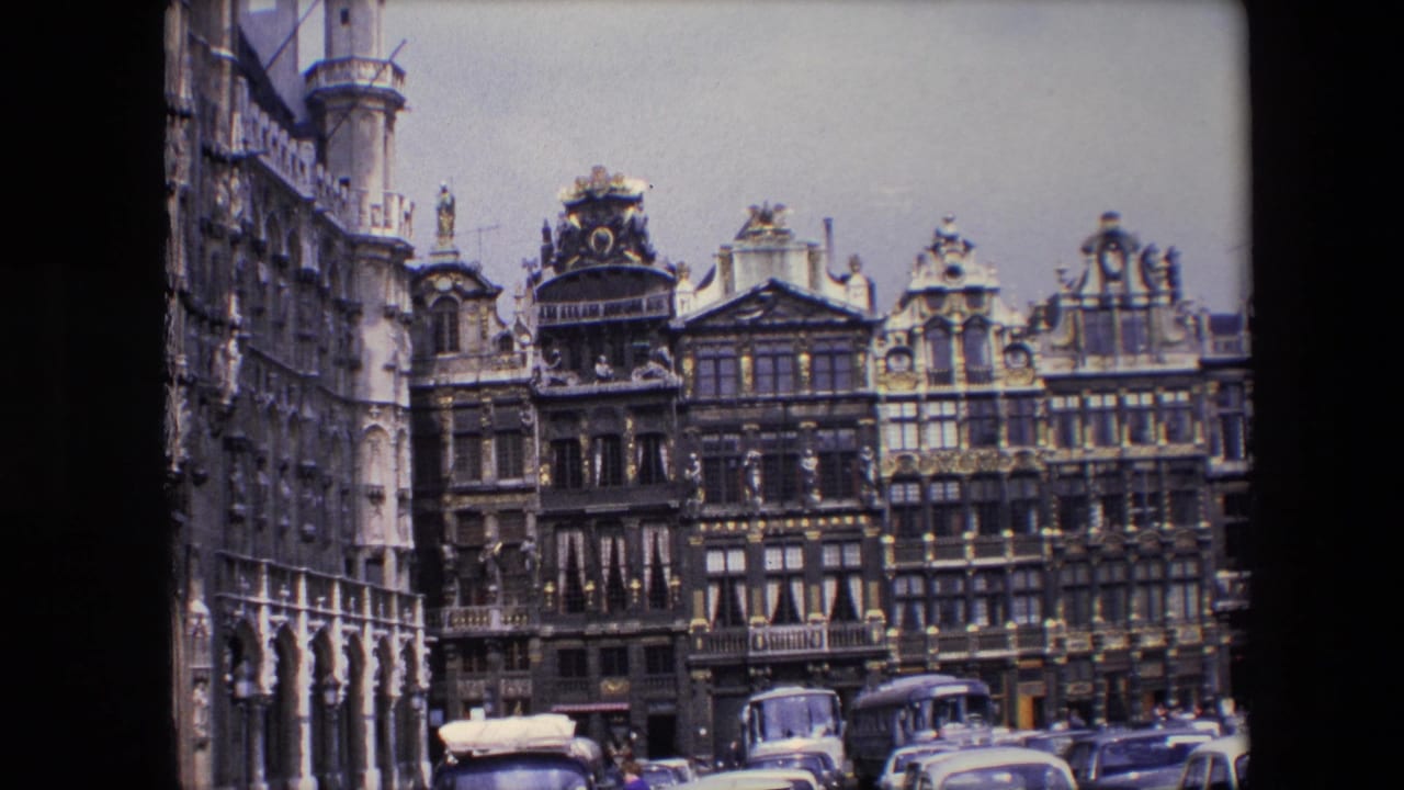 Historic facades with cars and a bus in front of the buildings.