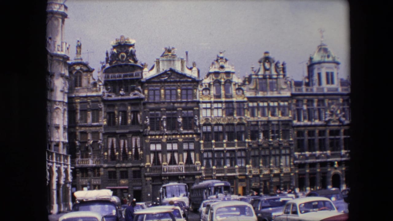 1967 8mm view of Brussels, Belgium, showing ornate Grand Place facades above parked mid-century cars and buses under an overcast sky.