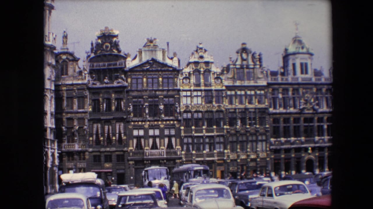 Historic gabled buildings line a busy square with cars and buses below.