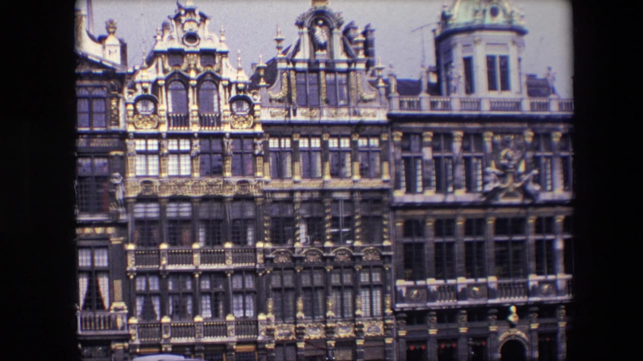 1967 8mm Brussels footage showing ornate historic facades with dark stonework, gilded decorative accents, sculpted details, and upper-story windows.