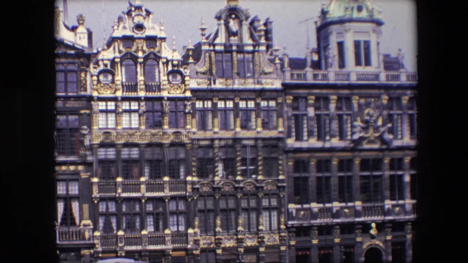 1967 8mm Brussels footage showing ornate historic facades with dark stonework, gilded decorative accents, sculpted details, and upper-story windows.